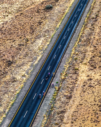 Aerial view of cyclists riding along a remote tar road through a dry drought stricken landscape in Cape Town Western Cape South Africa.