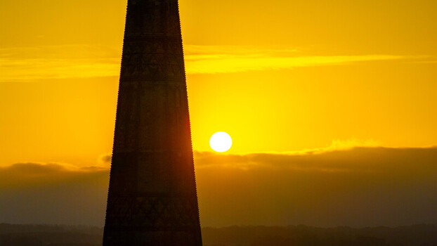 Aerial view of the Salisbury Cathedral spire silhouetted against a vibrant golden sunset sky over the historic city of Salisbury England United Kingdom. Aerial view of the Salisbury Cathedral spire silhouetted against a vibrant golden sunset sky over the historic city of Salisbury England United Kingdom.