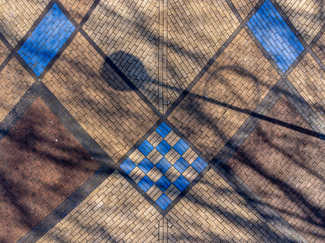 Aerial view of a patterned brick ground surface with a combination of earth toned and blue tiles casting tree shadows Maastrichtkwartier Flevoland Netherlands. Aerial view of a patterned brick ground surface with a combination of earth toned and blue tiles casting tree shadows Maastrichtkwartier Flevoland Netherlands.