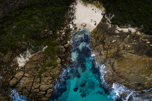 Aerial view of Conspicuous Cliff featuring rugged rock formations a secluded sandy cove and vibrant turquoise water along the coastline in Nornalup Western Australia Australia. Aerial view of Conspicuous Cliff featuring rugged rock formations a secluded sandy cove and vibrant turquoise water along the coastline in Nornalup Western Australia Australia.