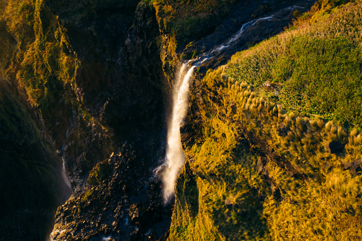 Aerial view of Poco da Ribeira do Ferreiro waterfall cascading down lush green cliffs during golden hour in Fajazinha Azores Portugal. Aerial view of Poco da Ribeira do Ferreiro waterfall cascading down lush green cliffs during golden hour in Fajazinha Azores Portugal.