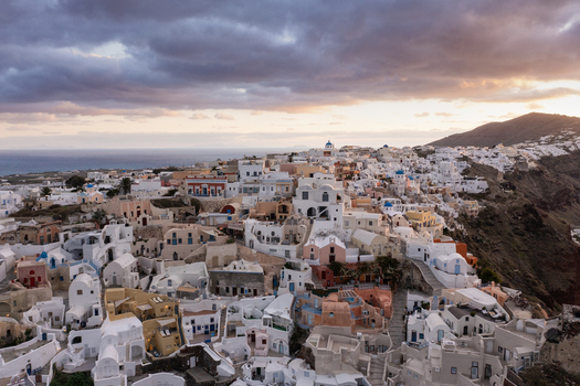 Aerial view of white washed buildings cascade down the volcanic cliffs towards the azure sea a captivating scene of architectural harmony against nature s grandeur Fira Thira Greece. Aerial view of white washed buildings cascade down the volcanic cliffs towards the azure sea a captivating scene of architectural harmony against nature s grandeur Fira Thira Greece.