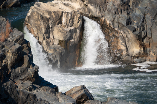 View of powerful waterfalls cascading between rugged dark rocks into a turbulent river creating a dynamic scene of nature s force Great Falls National Park Virginia United States. View of powerful waterfalls cascading between rugged dark rocks into a turbulent river creating a dynamic scene of nature s force Great Falls National Park Virginia United States.
