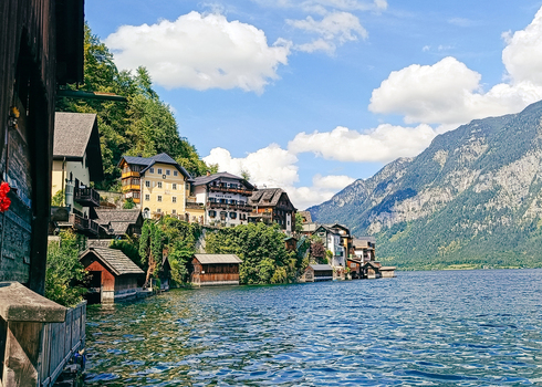 View of the historic village of Hallstatt with traditional alpine houses nestled along the lake shore under a bright blue sky in Hallstatt Upper Austria Austria. View of the historic village of Hallstatt with traditional alpine houses nestled along the lake shore under a bright blue sky in Hallstatt Upper Austria Austria.