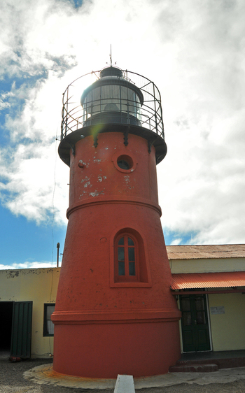 View of the red lighthouse tower of Puerto Piramides next to a building under a cloudy sky in Puerto Madryn Chubut Argentina. View of the red lighthouse tower of Puerto Piramides next to a building under a cloudy sky in Puerto Madryn Chubut Argentina.