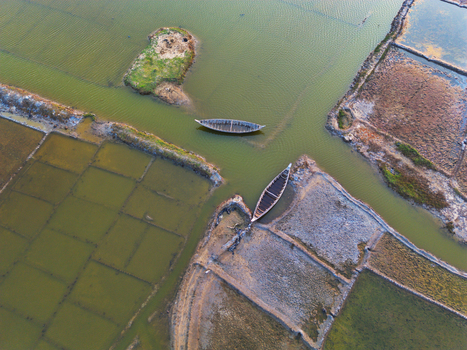 Aerial view of traditional wooden boats in salt pans with earthen embankments and a small island in Moheskhali Upazila Chittagong Division Bangladesh. Aerial view of traditional wooden boats in salt pans with earthen embankments and a small island in Moheskhali Upazila Chittagong Division Bangladesh.
