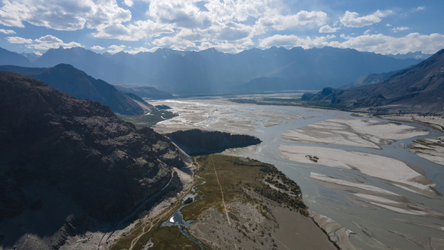 Aerial view of Shigar Valley featuring the wide braided riverbed of the Shigar River winding through rugged mountains under a bright sky in Shigar Gilgit Pakistan.
