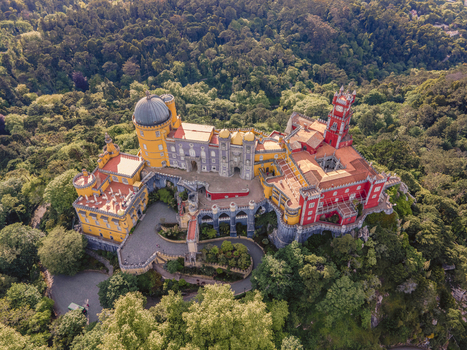 Aerial view of Pena Palace a colourful Romanticist castle building on hilltop during a beautiful sunset Sintra Lisbon Portugal.