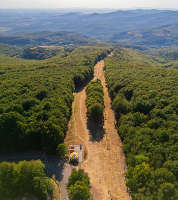 Aerial view of Kekesteto summit in the Matra mountains Hungary with forested slopes ski runs and hiking paths under clear summer skies in a protected natural landscape. Aerial view of Kekesteto summit in the Matra mountains Hungary with forested slopes ski runs and hiking paths under clear summer skies in a protected natural landscape.
