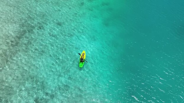 Aerial view of a person paddling a kayak in turquoise water Maldives Aerial view of a person paddling a kayak in turquoise water Maldives
