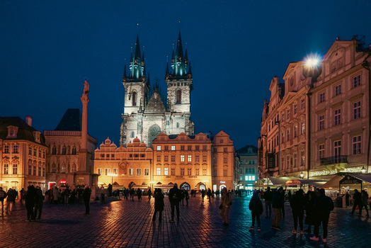 Prague Prague Czechia 03 November 2021 View of the Church of Our Lady before Tyn illuminated at night in the Old Town Square with people walking on the cobblestone pavement. Prague Prague Czechia 03 November 2021 View of the Church of Our Lady before Tyn illuminated at night in the Old Town Square with people walking on the cobblestone pavement.