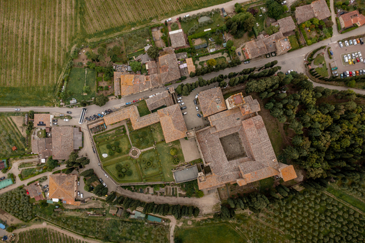Aerial view of the historic estate with its central courtyard formal gardens and terracotta rooftops surrounded by lush trees and agricultural fields in Passignano Toscana Italy. Aerial view of the historic estate with its central courtyard formal gardens and terracotta rooftops surrounded by lush trees and agricultural fields in Passignano Toscana Italy.