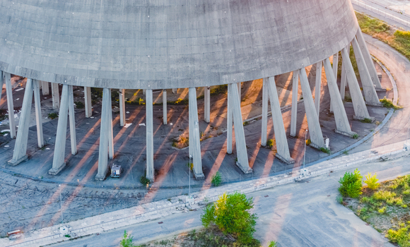 Aerial view of the massive concrete base and support columns of an industrial cooling tower in evening sunlight in Trino Piedmont Italy.
