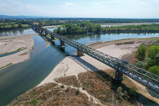Aerial view of the historic Ponte della Becca truss bridge crossing the river with sandy banks and green trees in Linarolo Lombardia Italy.