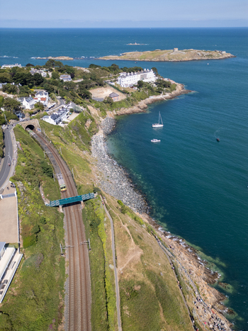 Aerial view of the Dalkey coastline featuring the railway line entering a tunnel coastal cliffs Dalkey Island and boats in the Irish Sea near Dublin County Dublin Ireland. Aerial view of the Dalkey coastline featuring the railway line entering a tunnel coastal cliffs Dalkey Island and boats in the Irish Sea near Dublin County Dublin Ireland.
