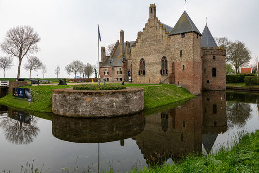 View of Radboud Castle with its brick walls and towers reflecting in the surrounding moat under an overcast sky Medemblik Noord Holland Netherlands. View of Radboud Castle with its brick walls and towers reflecting in the surrounding moat under an overcast sky Medemblik Noord Holland Netherlands.