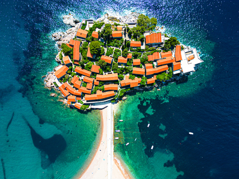 Aerial view of the historic islet of Sveti Stefan with terracotta rooftops and stone pathways surrounded by turquoise Adriatic waters in Sveti Stefan Budva Municipality Montenegro.