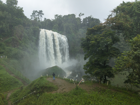 Aerial view of cascading Curugsewu waterfall amidst a lush green forest where mist kisses the vibrant foliage Curugsewu Kendal Regency Central Java Indonesia. Aerial view of cascading Curugsewu waterfall amidst a lush green forest where mist kisses the vibrant foliage Curugsewu Kendal Regency Central Java Indonesia.