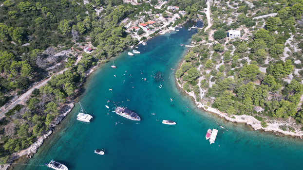 Aerial view of the turquoise waters of Necujam bay with boats anchored and people swimming surrounded by lush green pine forests in Necujam Split Dalmatia County Croatia. Aerial view of the turquoise waters of Necujam bay with boats anchored and people swimming surrounded by lush green pine forests in Necujam Split Dalmatia County Croatia.