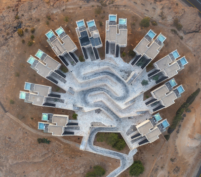 Aerial view of the Beresheet Hotel in the Negev desert featuring unique architecture with rooftop pools and winding pathways in Mitzpe Ramon South District Israel. Aerial view of the Beresheet Hotel in the Negev desert featuring unique architecture with rooftop pools and winding pathways in Mitzpe Ramon South District Israel.