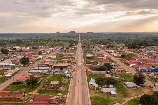Aerial view of Katakwi Town Council with the main road stretching through the town surrounded by buildings and green vegetation under a cloudy sky in Katakwi Eastern Region Uganda. Aerial view of Katakwi Town Council with the main road stretching through the town surrounded by buildings and green vegetation under a cloudy sky in Katakwi Eastern Region Uganda.