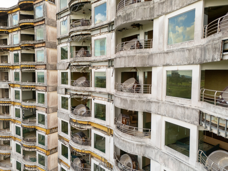Aerial view of the abandoned Sonesta One Resort featuring unfinished concrete structures curved balconies and large windows reflecting the sky in Jaco Provincia de Puntarenas Costa Rica. Aerial view of the abandoned Sonesta One Resort featuring unfinished concrete structures curved balconies and large windows reflecting the sky in Jaco Provincia de Puntarenas Costa Rica.