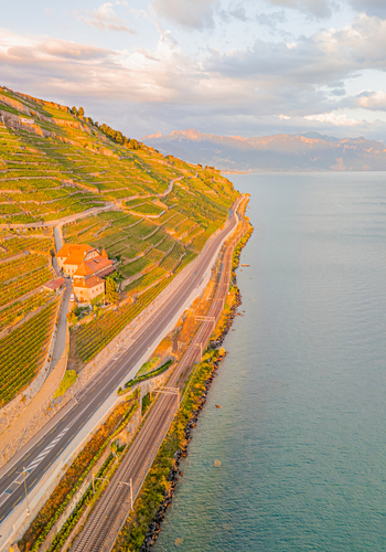 Aerial view of the terraced vineyards of Lavaux along the shores of Lake Geneva with a road and railway line at sunset Bourg en Lavaux Vaud Switzerland. Aerial view of the terraced vineyards of Lavaux along the shores of Lake Geneva with a road and railway line at sunset Bourg en Lavaux Vaud Switzerland.