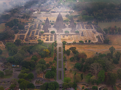 Aerial view of Prambanan Temple complex featuring ancient stone structures symmetrical layout and surrounding lush parkland in Kecamatan Prambanan Daerah Istimewa Yogya Indonesia.