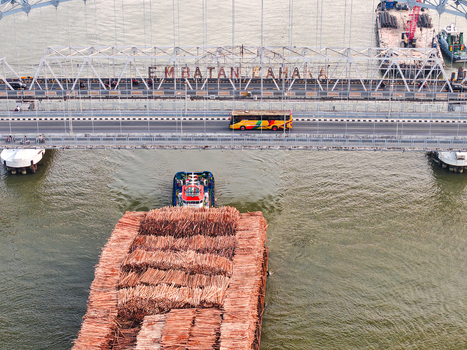 Aerial view of Jembatan Mahakam I bridge spanning the Mahakam River with a tugboat pulling a log barge and a bus crossing in Kecamatan Samarinda Seberang Kalimantan Timur Indonesia. Aerial view of Jembatan Mahakam I bridge spanning the Mahakam River with a tugboat pulling a log barge and a bus crossing in Kecamatan Samarinda Seberang Kalimantan Timur Indonesia.