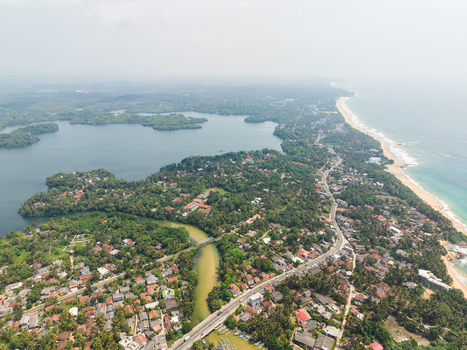 Aerial view of the coastal landscape featuring Dodanduwa Lake lush tropical vegetation and residential houses along the sandy shoreline in Dodanduwa Southern Province Sri Lanka. Aerial view of the coastal landscape featuring Dodanduwa Lake lush tropical vegetation and residential houses along the sandy shoreline in Dodanduwa Southern Province Sri Lanka.
