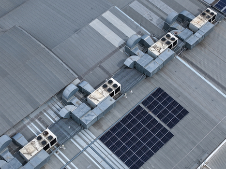 Aerial view of industrial rooftop featuring multiple HVAC ventilation units and solar panel arrays on a metal roof structure in Melbourne VIC Australia.