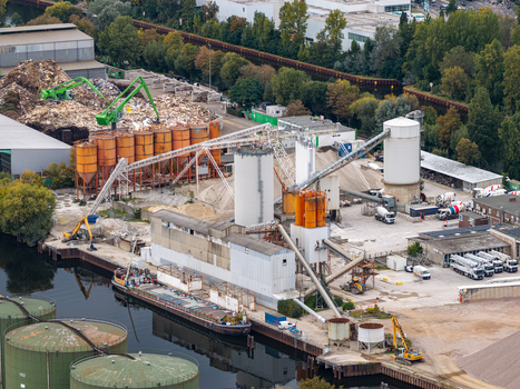 Aerial view of the Klarwerk Ruhleben industrial facility featuring silos conveyor systems and a barge docked on the river in Berlin Berlin Germany.