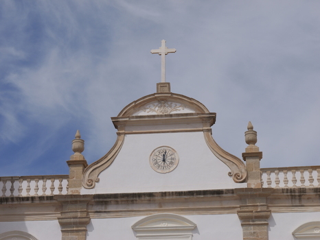 View of the white facade of the Se de Portalegre cathedral featuring a stone cross and a sundial under a blue sky in Portalegre Portalegre District Portugal.