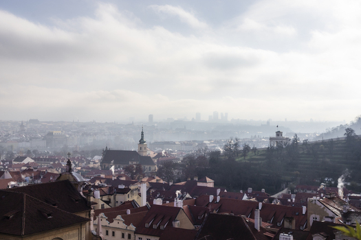 View of the historic red rooftops and church spires of the Mala Strana district under a misty morning sky in Prague Prague Czechia. View of the historic red rooftops and church spires of the Mala Strana district under a misty morning sky in Prague Prague Czechia.
