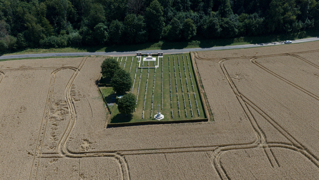 Aerial view of Delville Wood Cemetery surrounded by golden wheat fields and lush trees in the countryside Longueval Hauts de France France.