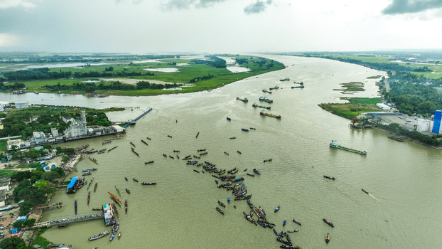 Baghabari Rajshahi Division Bangladesh 20 August 2022 Aerial view of Baghabari river port with many boats and cargo vessels surrounded by green fields and industrial buildings.