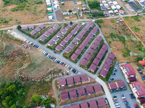 Aerial view of the Arapya holiday resort featuring numerous small cabins arranged in rows parking areas and surrounding green landscape in Burgas Bulgaria. Aerial view of the Arapya holiday resort featuring numerous small cabins arranged in rows parking areas and surrounding green landscape in Burgas Bulgaria.