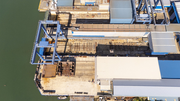 Aerial view of the industrial port area in Zumaia featuring large gantry cranes storage yards and warehouse structures along the waterfront in Zumaia Basque Country Spain.