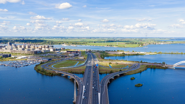 Aerial view of the A10 motorway interchange and S114 junction crossing the water with modern buildings a marina and green fields in Amsterdam Noord Holland Netherlands. Aerial view of the A10 motorway interchange and S114 junction crossing the water with modern buildings a marina and green fields in Amsterdam Noord Holland Netherlands.