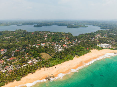 Aerial view of the tropical coastline with sandy beaches turquoise ocean waves and lush greenery near the lagoon in Dodanduwa Southern Province Sri Lanka. Aerial view of the tropical coastline with sandy beaches turquoise ocean waves and lush greenery near the lagoon in Dodanduwa Southern Province Sri Lanka.