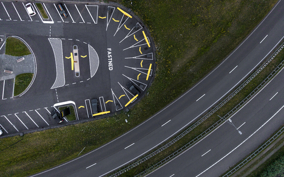 Aerial view of a Fastned electric vehicle charging station with parked cars and road markings located next to a highway in Amsterdam Noord Holland Netherlands. Aerial view of a Fastned electric vehicle charging station with parked cars and road markings located next to a highway in Amsterdam Noord Holland Netherlands.