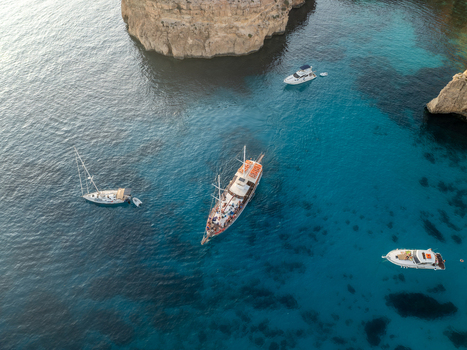 Aerial view of boats floating on the turquoise waters of the Blue Lagoon a vibrant contrast to the rugged cliffs Blue lagoon Comino Malta. Aerial view of boats floating on the turquoise waters of the Blue Lagoon a vibrant contrast to the rugged cliffs Blue lagoon Comino Malta.