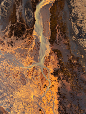 Aerial view of a braided river system with sediment rich water flowing through a volcanic landscape in Iceland. Aerial view of a braided river system with sediment rich water flowing through a volcanic landscape in Iceland.