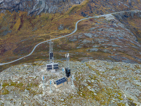 Aerial view of telecommunication towers solar panels and small wind turbines on a rocky mountain peak with a winding road in Andalsnes More og Romsdal Norway.