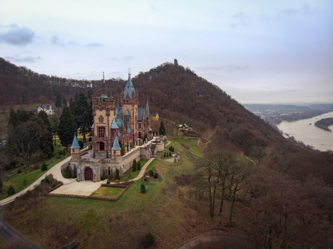Aerial view of Schloss Drachenburg with its ornate towers and spires on a wooded hillside overlooking the Rhine river Cologne North Rhine Westphalia Germany.