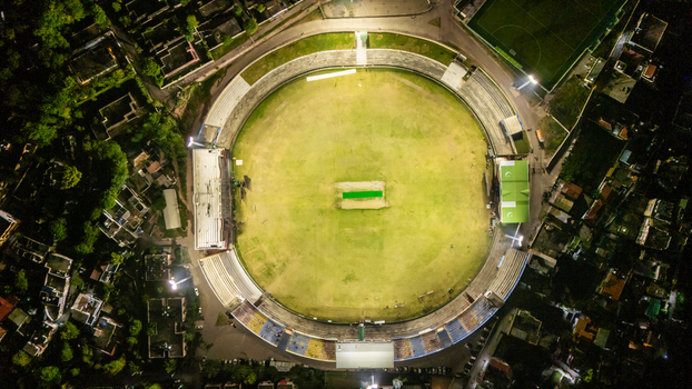 Aerial view of the illuminated Muzaffarabad Cricket Stadium at night surrounded by urban rooftops and trees in Muzaffarabad Azad Kashmir Pakistan. Aerial view of the illuminated Muzaffarabad Cricket Stadium at night surrounded by urban rooftops and trees in Muzaffarabad Azad Kashmir Pakistan.