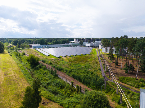 Olaine parish Latvia 04 July 2026 Aerial view of a solar panel farm surrounded by green fields trees and industrial buildings under a cloudy sky. Olaine parish Latvia 04 July 2026 Aerial view of a solar panel farm surrounded by green fields trees and industrial buildings under a cloudy sky.