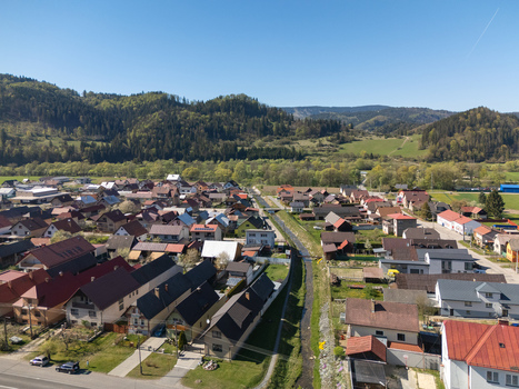 Aerial view of the village houses with red roofs and a narrow canal surrounded by forested hills in Kriva Zilina Region Slovakia.