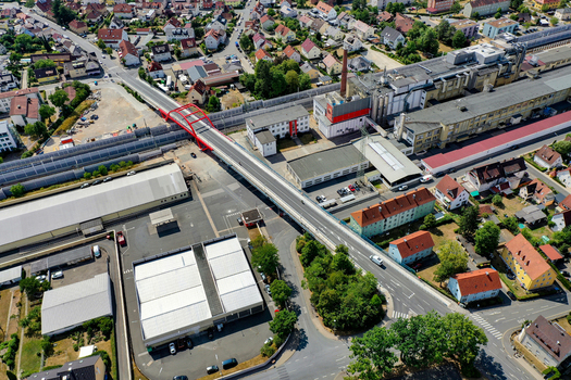 Aerial view of the red Piastenbrucke bridge crossing railway tracks near industrial buildings and residential houses in Forchheim Bayern Germany.