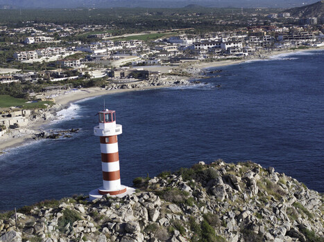 Aerial view of the red and white striped Cabo San Lucas Lighthouse on a rocky cliff overlooking the Pacific Ocean in Cabo San Lucas Baja California Sur Mexico.